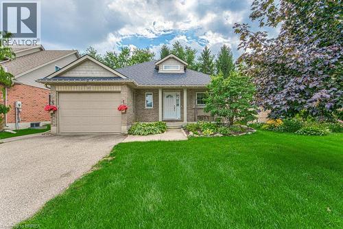 Brick exterior with decorative dormer, attached garage, and mature landscaping - 423 Poldon Drive, Norwich, ON 