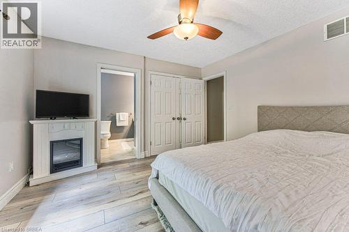 Wood-finish flooring, ceiling fan, white paneled doors, and a decorative electric fireplace - 423 Poldon Drive, Norwich, ON 