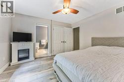 Wood-finish flooring, ceiling fan, white paneled doors, and a decorative electric fireplace - 