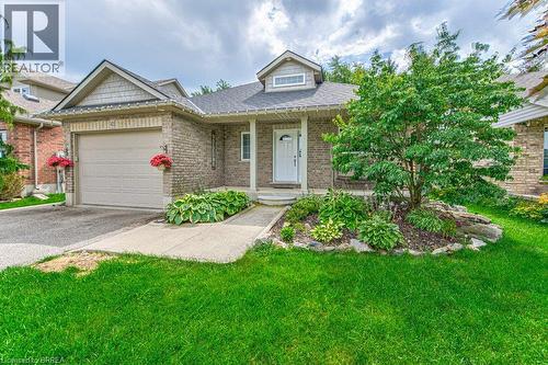 Brick exterior with a peaked roofline, front porch, and an attached garage with a paved driveway - 423 Poldon Drive, Norwich, ON 