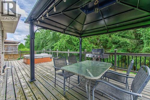 Expansive outdoor deck featuring a hot tub, gazebo, and surrounding mature trees - 423 Poldon Drive, Norwich, ON 