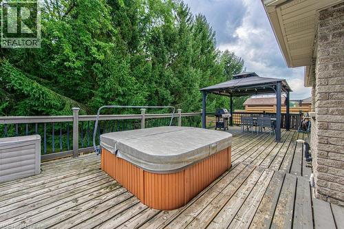 Expansive wood deck featuring a covered hot tub, a detached gazebo, and a brick exterior - 423 Poldon Drive, Norwich, ON 
