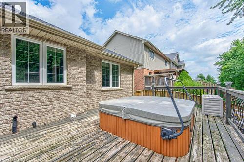Exterior brick facade with multiple windows, leading to a wooden deck featuring a built-in spa - 423 Poldon Drive, Norwich, ON 