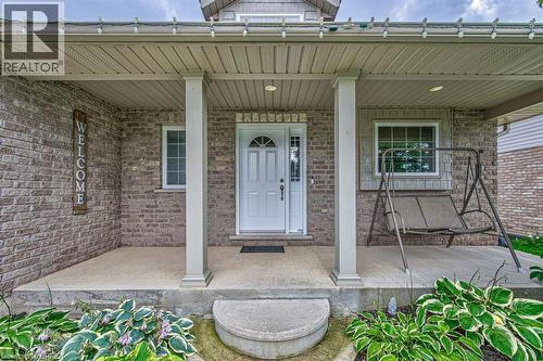 Brick facade with a covered porch featuring white columns - 423 Poldon Drive, Norwich, ON 