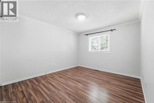 Wood-finish flooring, white painted walls, crown molding, and a single window with blinds - 449 Exmoor Street, Waterloo, ON 