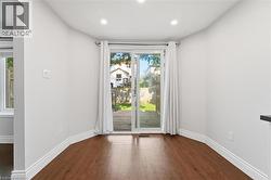 Recessed lighting illuminates wood-finish flooring, white walls, and a sliding glass door leading to an outdoor deck - 