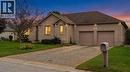 Brick exterior featuring a two-car garage with individual doors, a paved driveway, and established landscaping - 515 Woodward Drive, Mount Brydges, ON 