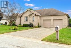 Brick exterior with multiple windows, an attached two-car garage, and a paver driveway - 