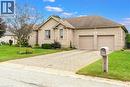 Brick exterior with multiple windows, an attached two-car garage, and a paver driveway - 515 Woodward Drive, Mount Brydges, ON 