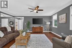 Hardwood flooring, painted walls, crown molding, ceiling fan with integrated lighting, and multiple windows with blinds - 