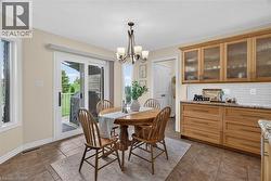 Light-toned cabinetry with glass-front uppers, a subway tile backsplash, and a sliding glass door to the exterior - 