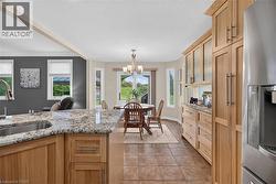 Kitchen featuring wood cabinetry, stainless steel appliances, a kitchen island with sink, and granite countertops - 