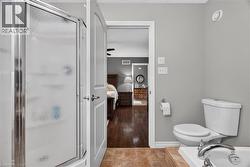 Enclosed shower with textured glass, white toilet, and brown tile flooring - 