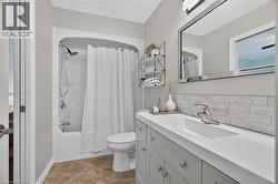White subway tile backsplash, integrated rectangular sink, chrome faucet, mirrored vanity, and light gray vanity cabinetry - 