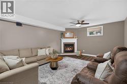 Corner fireplace with a white mantel, wood-finish flooring, and a ceiling fan - 