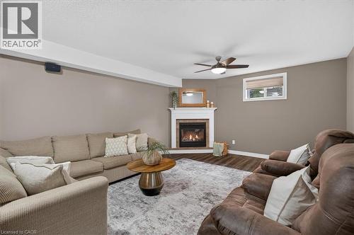 Corner fireplace with a white mantel, wood-finish flooring, and a ceiling fan - 515 Woodward Drive, Mount Brydges, ON 