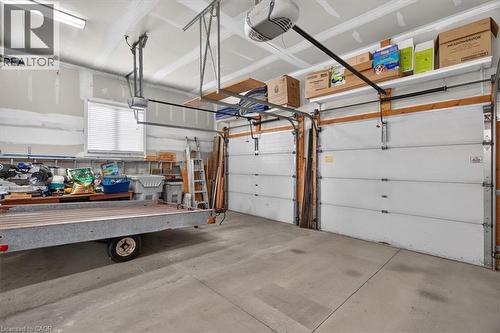 Attached two-car garage featuring automatic door openers, concrete flooring, and an elevated storage shelf - 515 Woodward Drive, Mount Brydges, ON 
