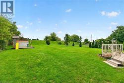 Expansive green lawn with mature trees, established landscaping, and a multi-level wooden deck - 