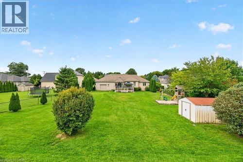 Expansive green lawn with mature landscaping, a utility shed, and a playset structure - 515 Woodward Drive, Mount Brydges, ON 