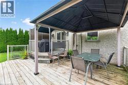 Expansive wood-finish deck with a built-in privacy wall, glass panel railings, and a two-tier design - 