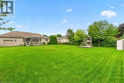 Expansive backyard with a large lawn, mature trees, and a ground-level deck featuring a gazebo - 