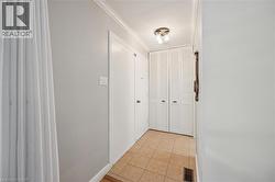 Tiled flooring, crown molding, white louvered closet doors, and flush mount lighting - 