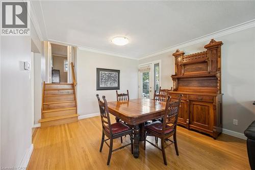 Hardwood flooring, light gray wall tones, crown molding, a built-in staircase, and a rear door with an exterior view - 35 Crosby Drive, Kitchener, ON 