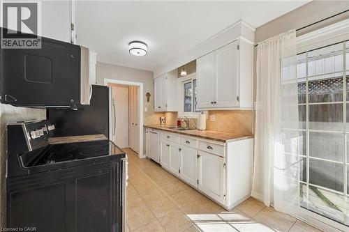 Kitchen featuring white cabinetry, tile flooring, full-size appliances, and a glass sliding door - 35 Crosby Drive, Kitchener, ON 
