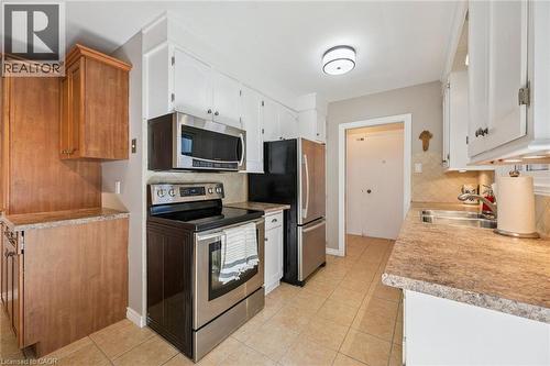 Kitchen featuring a stainless steel appliance suite, tiled flooring, white upper cabinetry, light wood-finish lower cabinetry, and light-toned countertops - 35 Crosby Drive, Kitchener, ON 