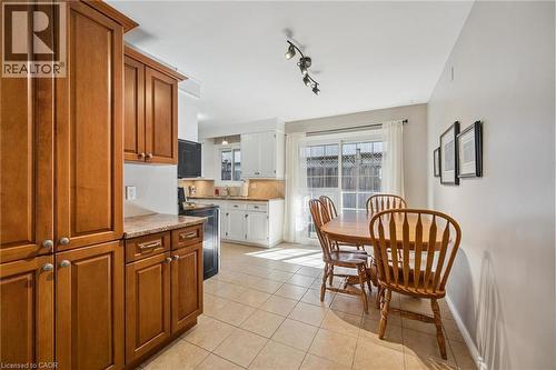 Porcelain tile flooring, light wood cabinetry, integrated kitchen appliances, track lighting, and a sliding glass door - 35 Crosby Drive, Kitchener, ON 