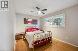 Wood-finish flooring, single window with blinds, ceiling fan with integrated lighting, and neutral wall tones - 