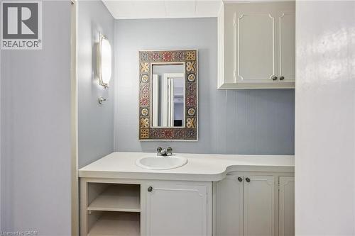 Built-in vanity with integrated sink, white countertop, white cabinetry with dark hardware, built-in shelving, and wall-mounted lighting - 35 Crosby Drive, Kitchener, ON 