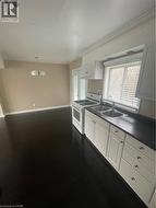 Kitchen with gas range, hanging light fixtures, white cabinetry - 