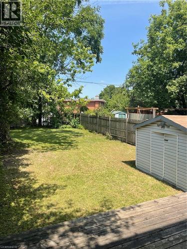 Expansive green lawn with mature perimeter trees, wood fence, and a storage shed - 124 Avalon Place, Kitchener, ON 