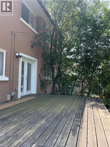 Wood-plank outdoor deck with double glass-pane doors, brick exterior, and mature trees - 124 Avalon Place, Kitchener, ON 