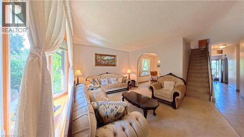 Natural light entry, arched doorway, carpeted living area, tile flooring, and staircase - 56 Scenic Wood Crescent, Kitchener, ON 