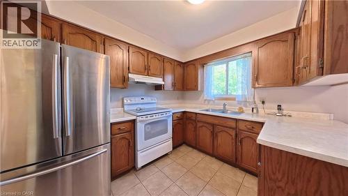 Kitchen featuring wood cabinetry, white countertops, a stainless steel refrigerator, and tiled flooring - 56 Scenic Wood Crescent, Kitchener, ON 