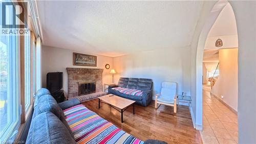 Brick fireplace with hearth, wood-finish flooring, large multi-pane windows, and an arched doorway - 56 Scenic Wood Crescent, Kitchener, ON 