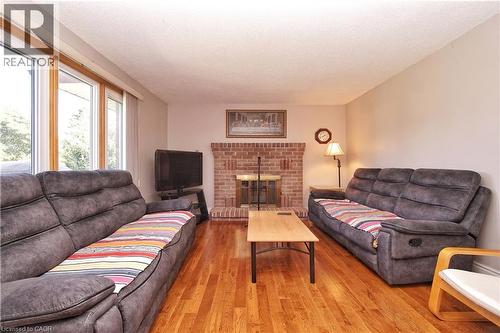 Brick fireplace with hearth, hardwood flooring, and large picture windows - 56 Scenic Wood Crescent, Kitchener, ON 