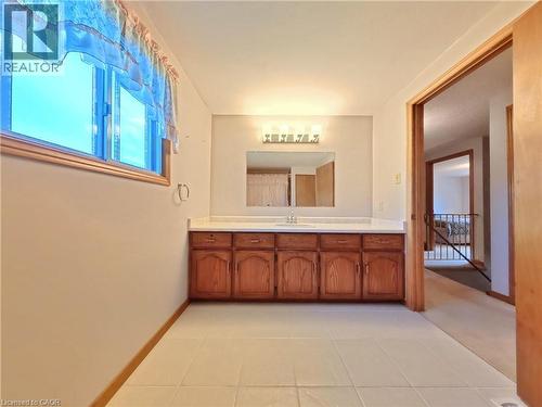 Long vanity with wood-finish cabinetry, white countertop, and integrated sink - 56 Scenic Wood Crescent, Kitchener, ON 