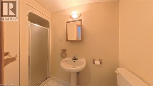 Pedestal sink, wall-mounted mirror, shower enclosure, porcelain toilet, and wall-mounted light fixture - 56 Scenic Wood Crescent, Kitchener, ON 