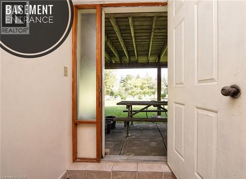 Panel door with a classic knob hardware, wood-framed sidelight, and tiled threshold leading to an exterior covered patio - 56 Scenic Wood Crescent, Kitchener, ON 