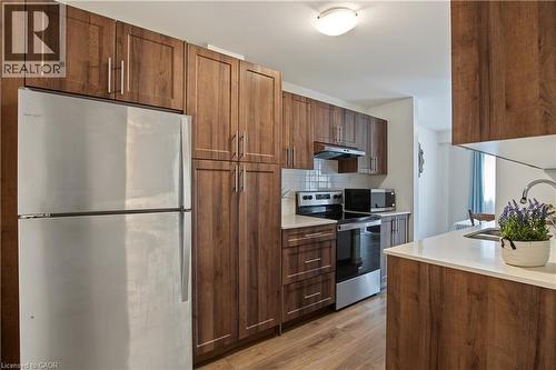 Contemporary kitchen featuring wood-finish cabinetry, stainless steel appliances, white subway tile backsplash, and light-toned countertops - 1444 Upper Ottawa Street Unit# 32, Hamilton, ON 