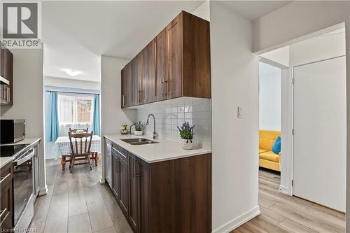 Galley kitchen featuring wood-finish cabinetry, white countertops, and a white subway tile backsplash - 1444 Upper Ottawa Street Unit# 32, Hamilton, ON 