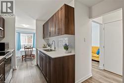 Galley kitchen featuring wood-finish cabinetry, white countertops, and a white subway tile backsplash - 