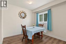 Wood-finish flooring with white baseboards, a window with white trim, and a flush mount ceiling light - 