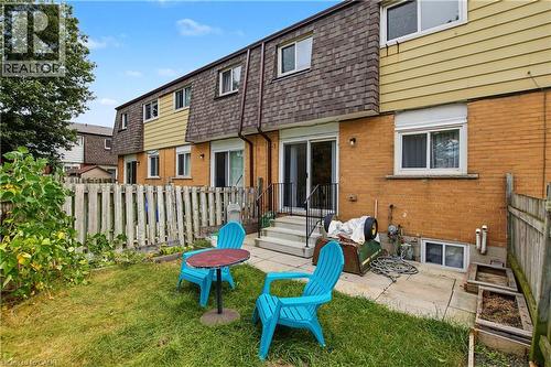 Rear exterior featuring brick and horizontal siding, a private fenced yard with a manicured lawn, and a ground-level patio - 1444 Upper Ottawa Street Unit# 32, Hamilton, ON 