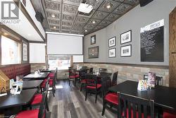 Decorative pressed-tin ceiling tiles, projector with retractable screen, wood-finish flooring, stone-veneer wall accents, and recessed lighting - 