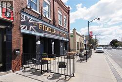 Brick facade commercial building with a prominent storefront, exterior lighting fixtures, and an outdoor patio area enclosed by black railings - 