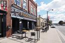 Brick facade commercial building with a prominent storefront, exterior lighting fixtures, and an outdoor patio area enclosed by black railings - 707 E King Street E, Cambridge, ON 